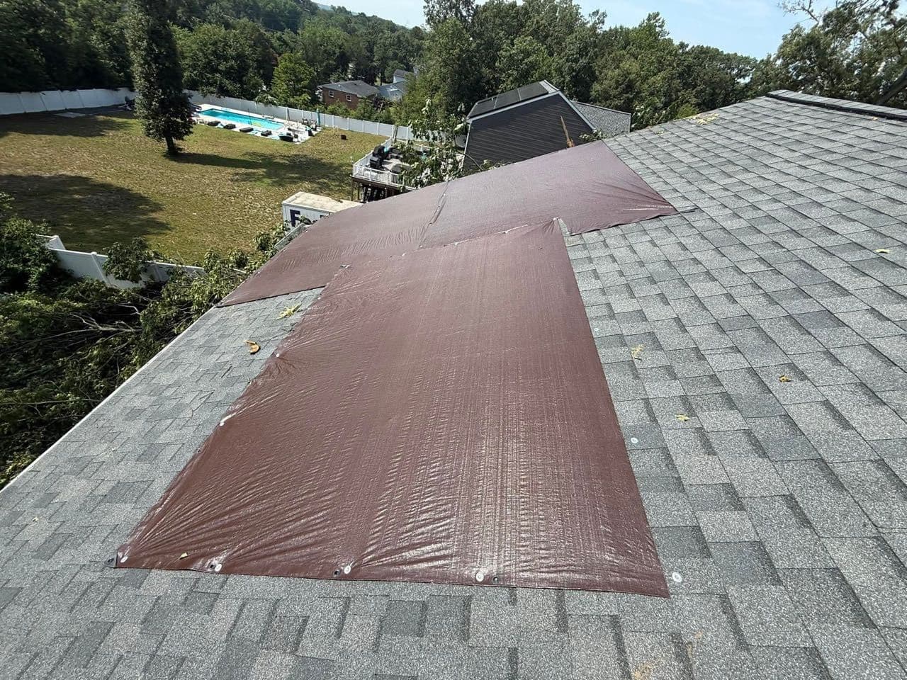Emergency brown roof tarp secured over storm damage in Severn, Maryland by Apper Construction to stop leaks
