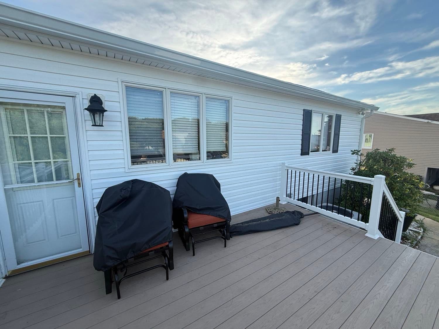 New white CertainTeed Dutchlap vinyl siding, wrapped trim and black shutters along the composite-deck side of a Pasadena, Maryland home