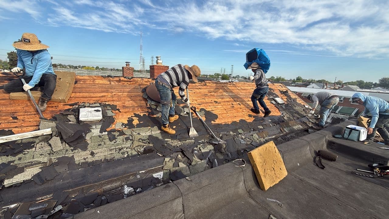 Roofing crew tearing off an old worn roof down to the deck on a Maryland home by Apper Construction